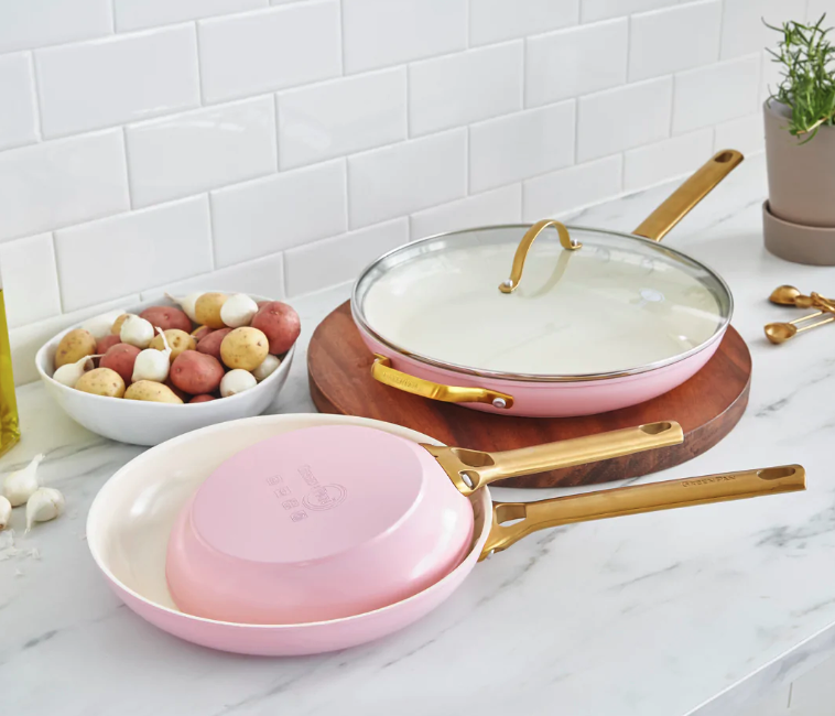a set of three pink frying pans with gold handles