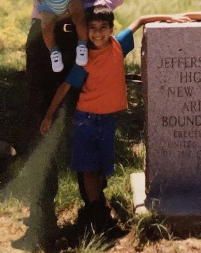 small kid posing with attitude in front of a grave