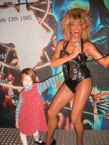 a young kid posing with the wax figure of tina