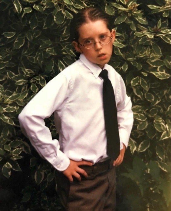 a kid in a suit posing with both hands on hips