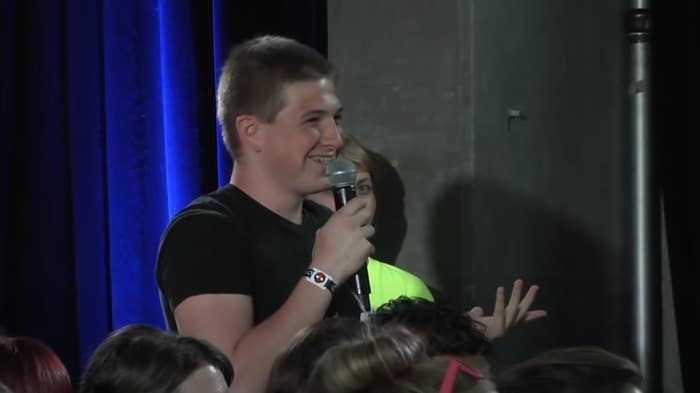 Person in the audience smiling and holding a microphone