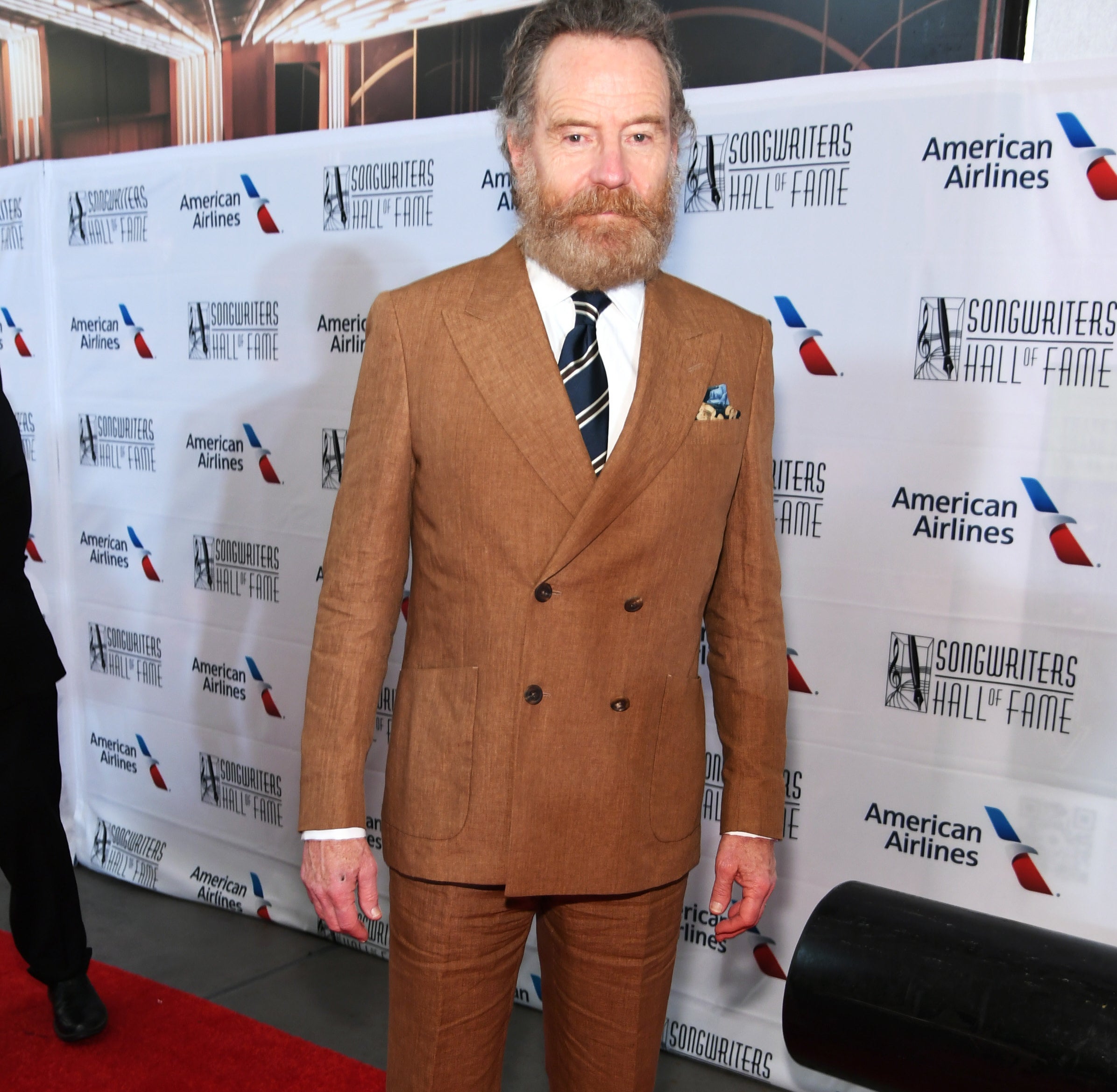 Bryan in a suit and tie and with a beard on the red carpet