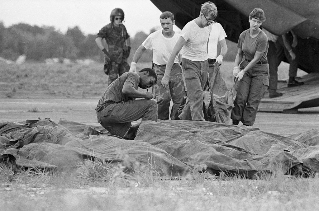 People examine bodies in a field