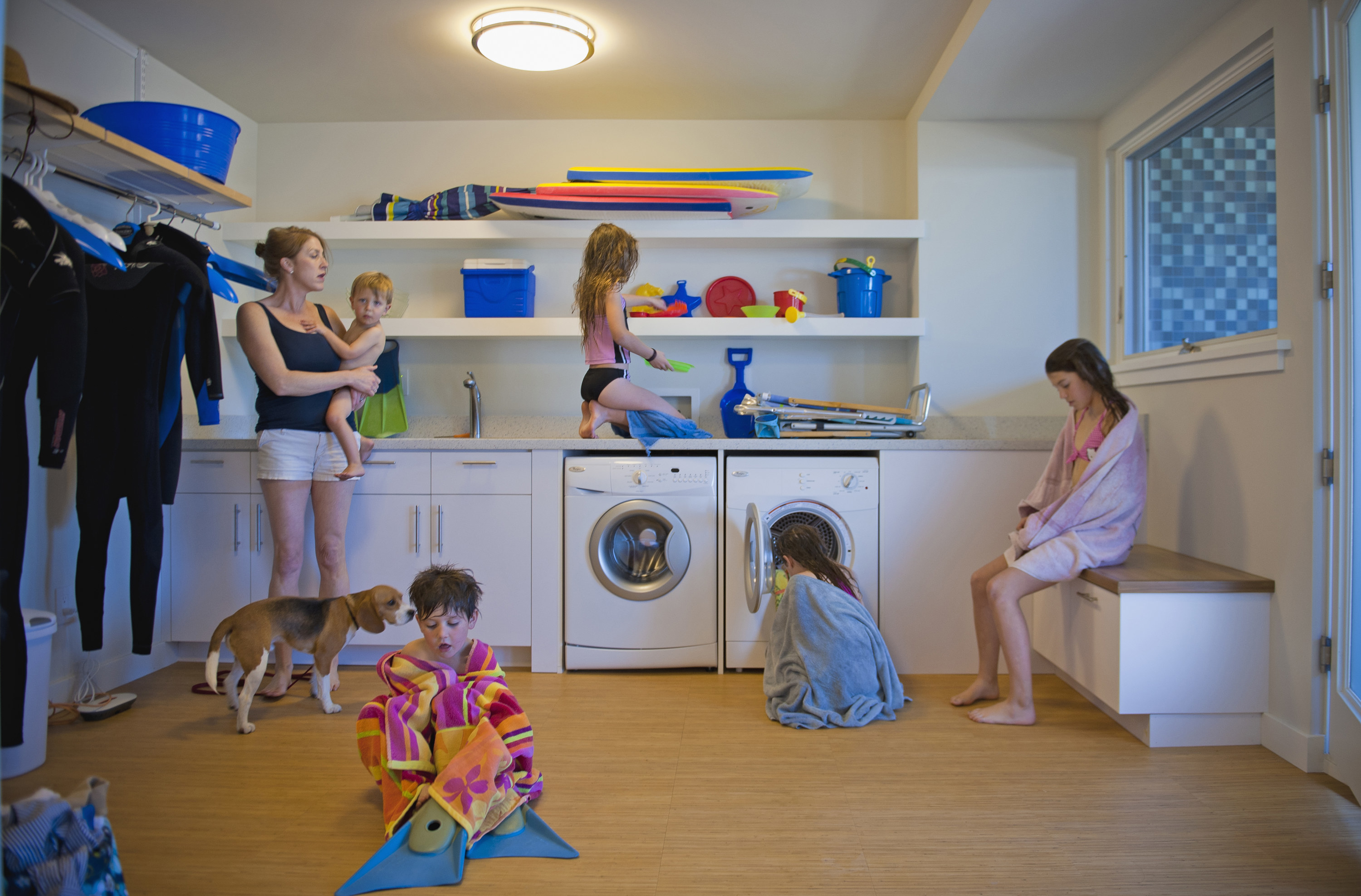 A mom holds her baby while talking to her four other kids in their laundry room