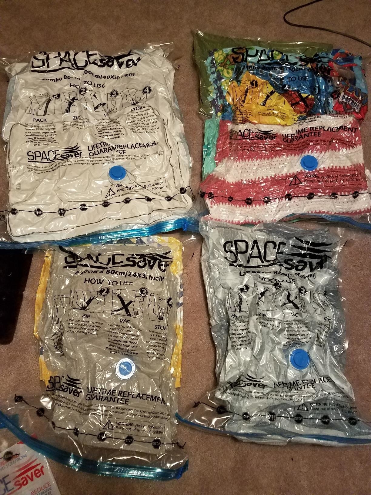 Reviewer image of blankets, pillows, comforters, and more in four vacuum bags