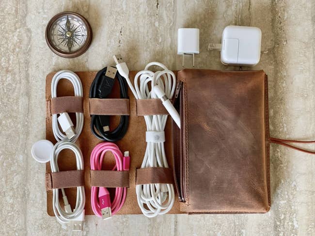 The leather organizer with several cords neatly organized is shown