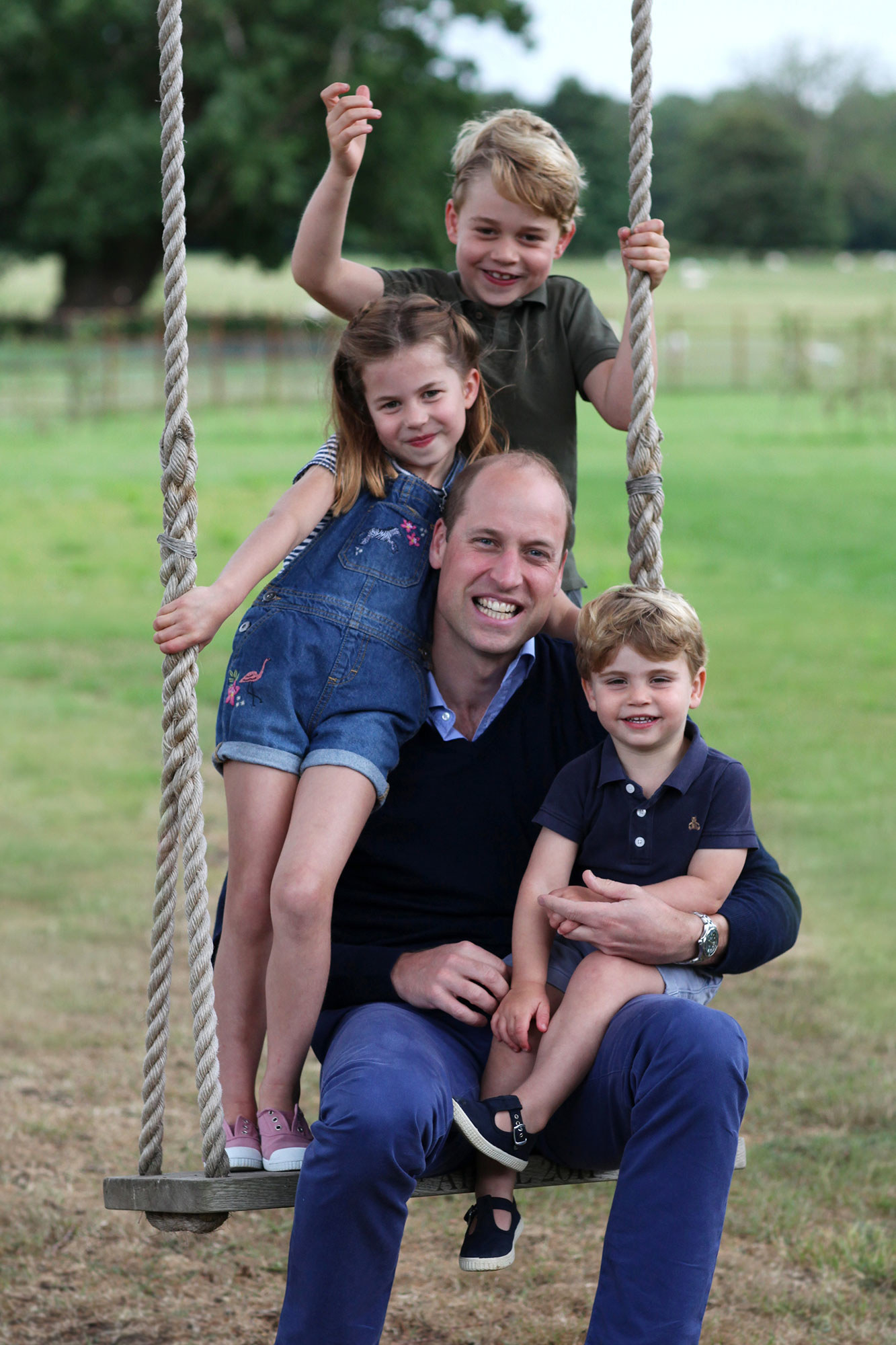 William sitting on a swing with one son sitting on his lap and two of his other children standing