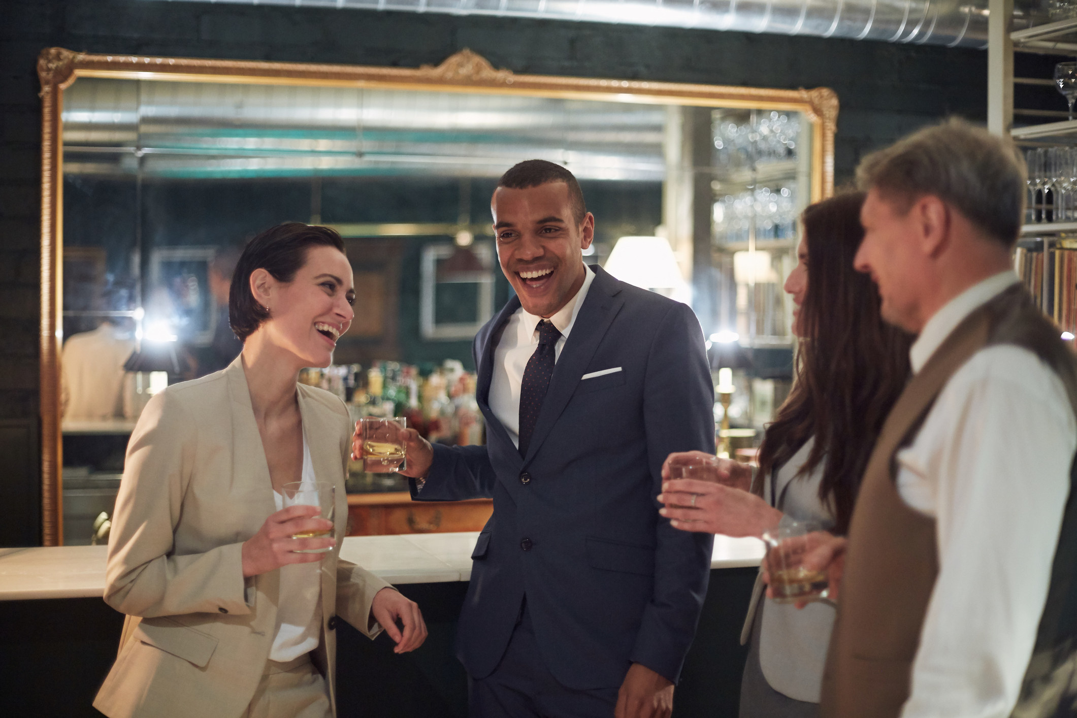 A group of nicely dressed people drinking at a bar