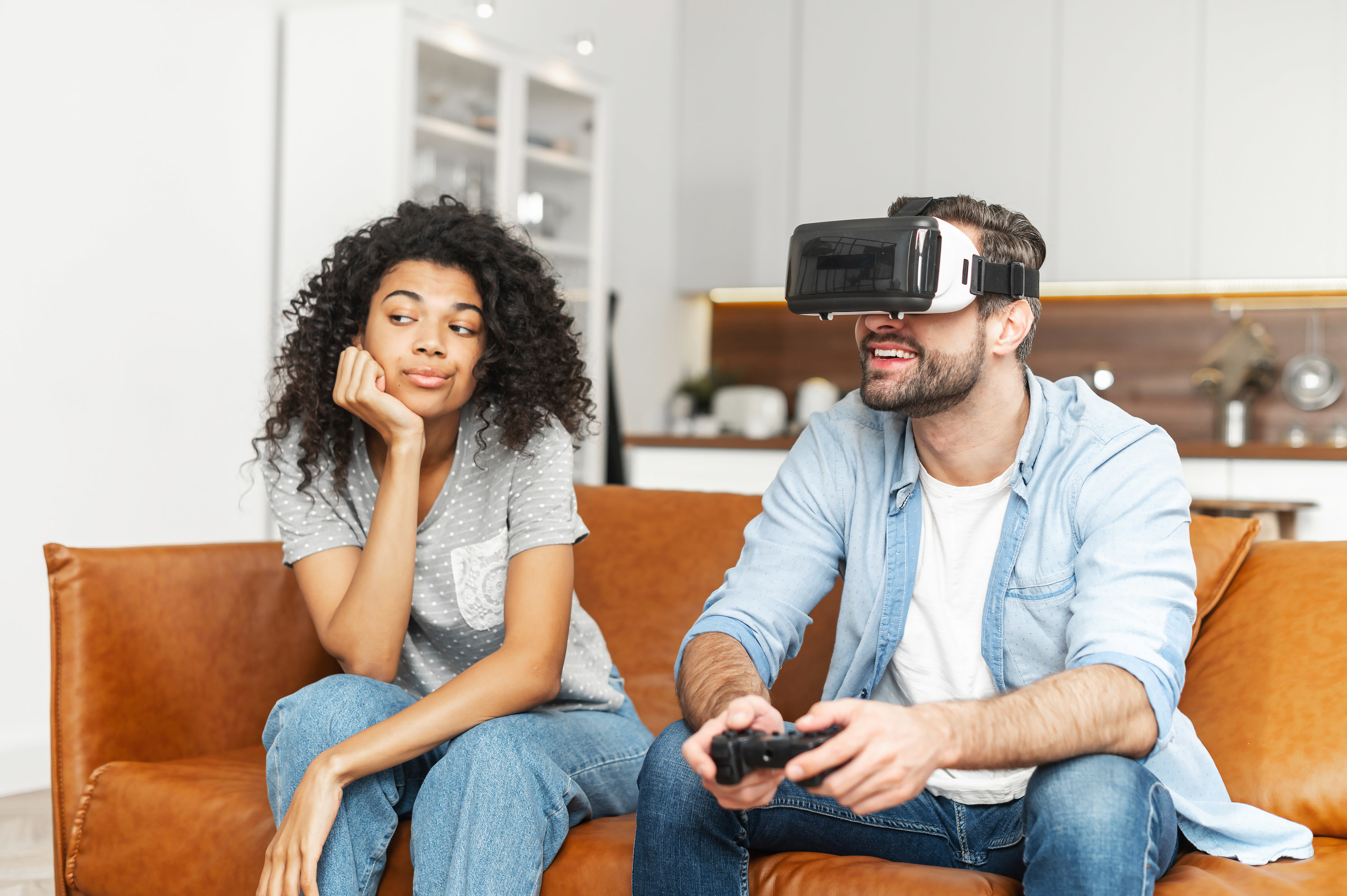 woman looking bored while her husband sits next to her playing video games
