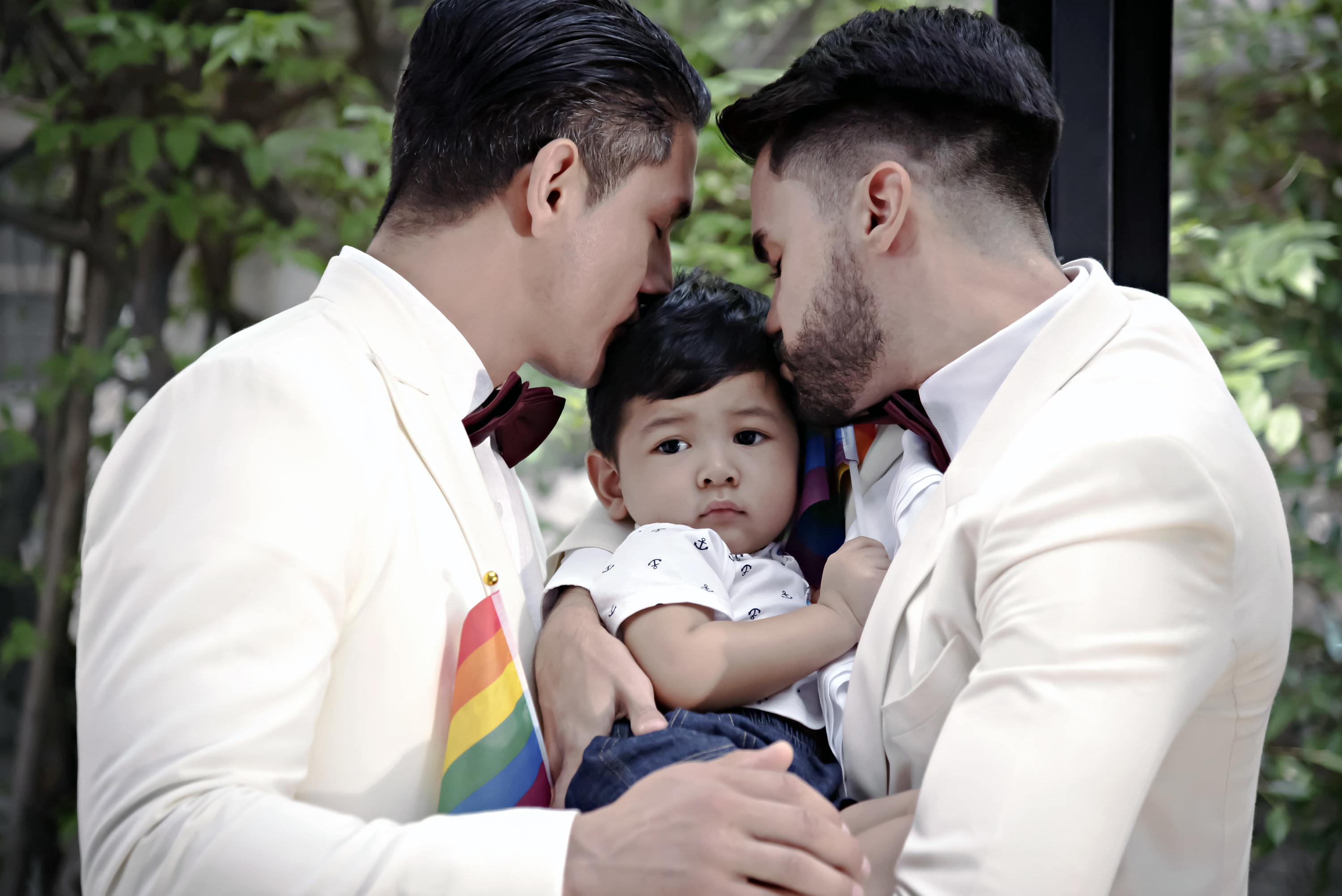 Two men kiss their baby