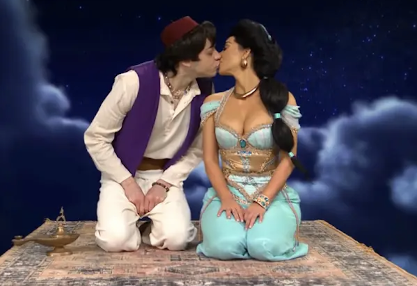 Pete dressed as Aladdin and Kim dressed as Jasmine kissing on a magic carpet ride