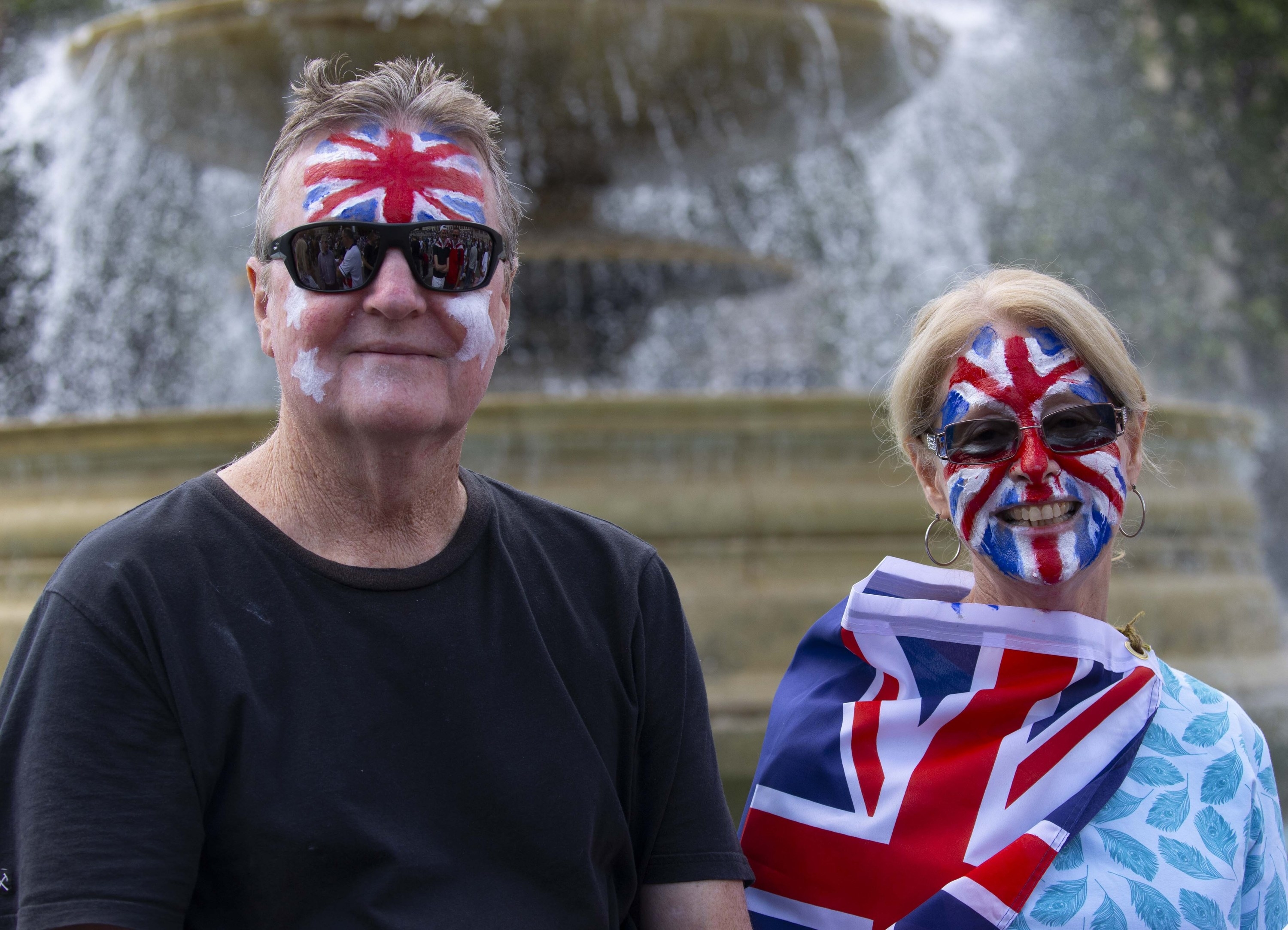 Two citizens with the UK flag painted on their faces, and one is draped in an actual UK flag