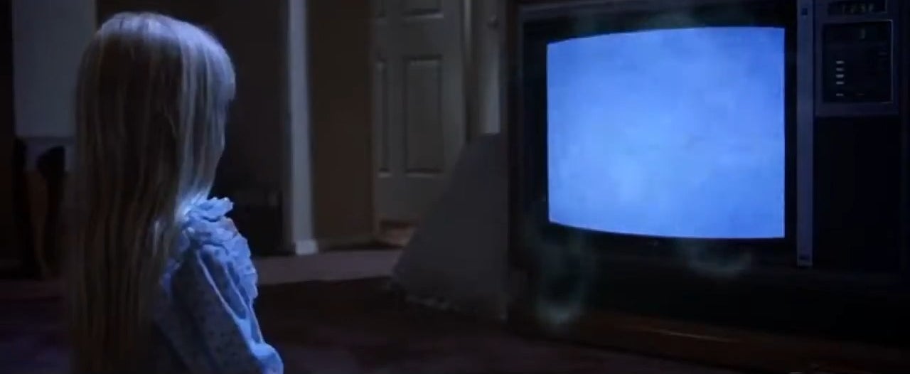 Carol Anne kneeling in front of a TV as spirits emerge from it in &quot;Poltergeist&quot;