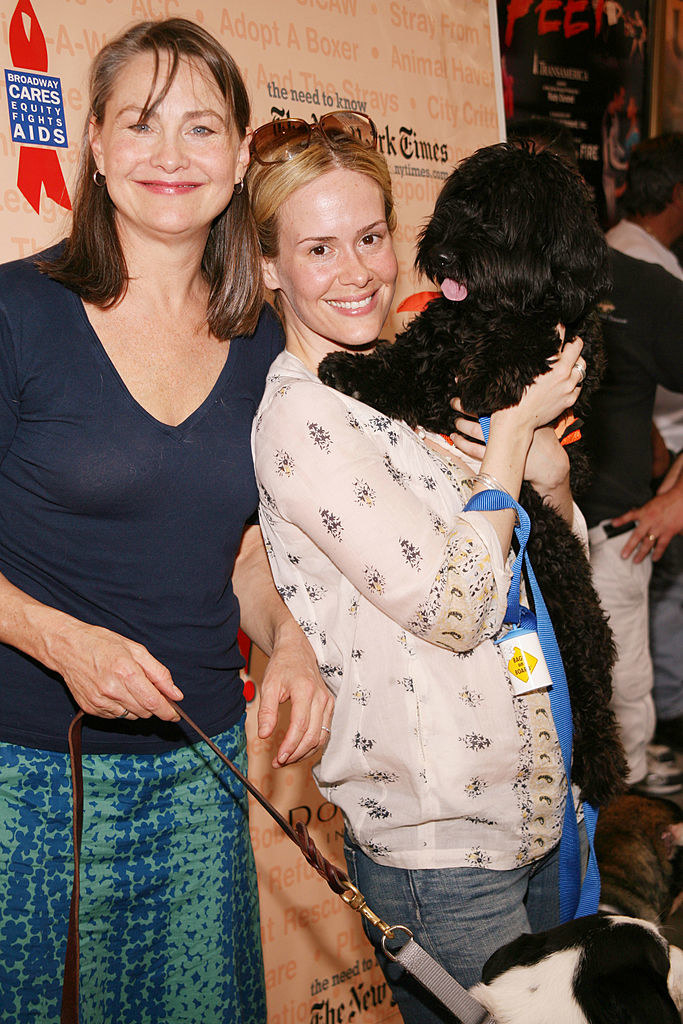 Sara holding a dog in her arms and Cherry holding one from their leash