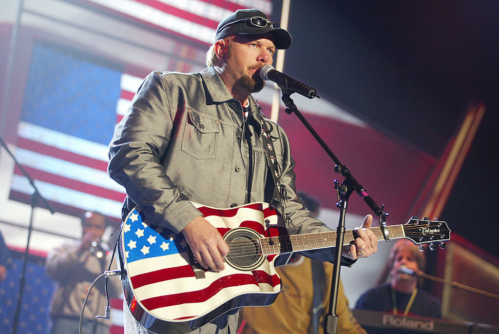 a country singer playing a guitar with an american flag on it