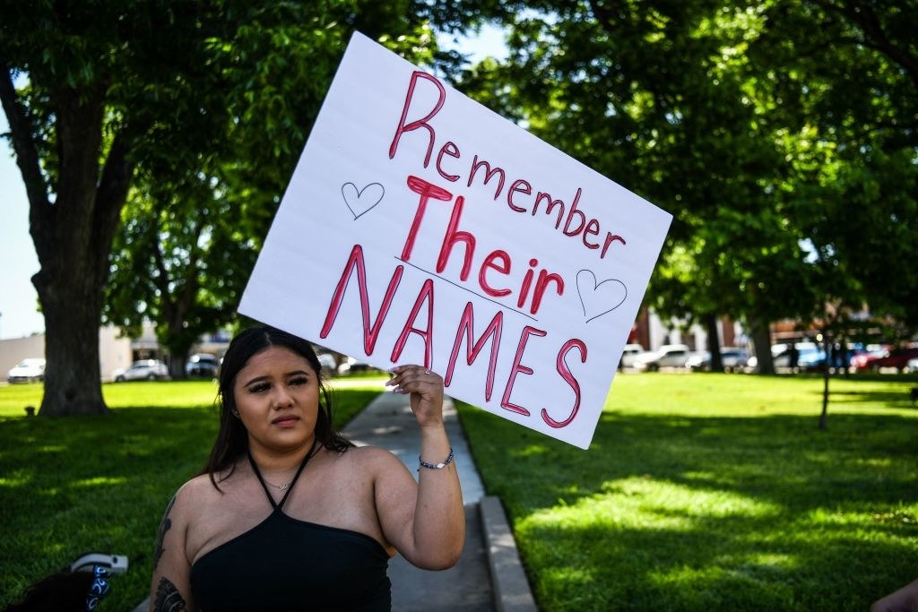 a woman holding a sign that reads, remember their names
