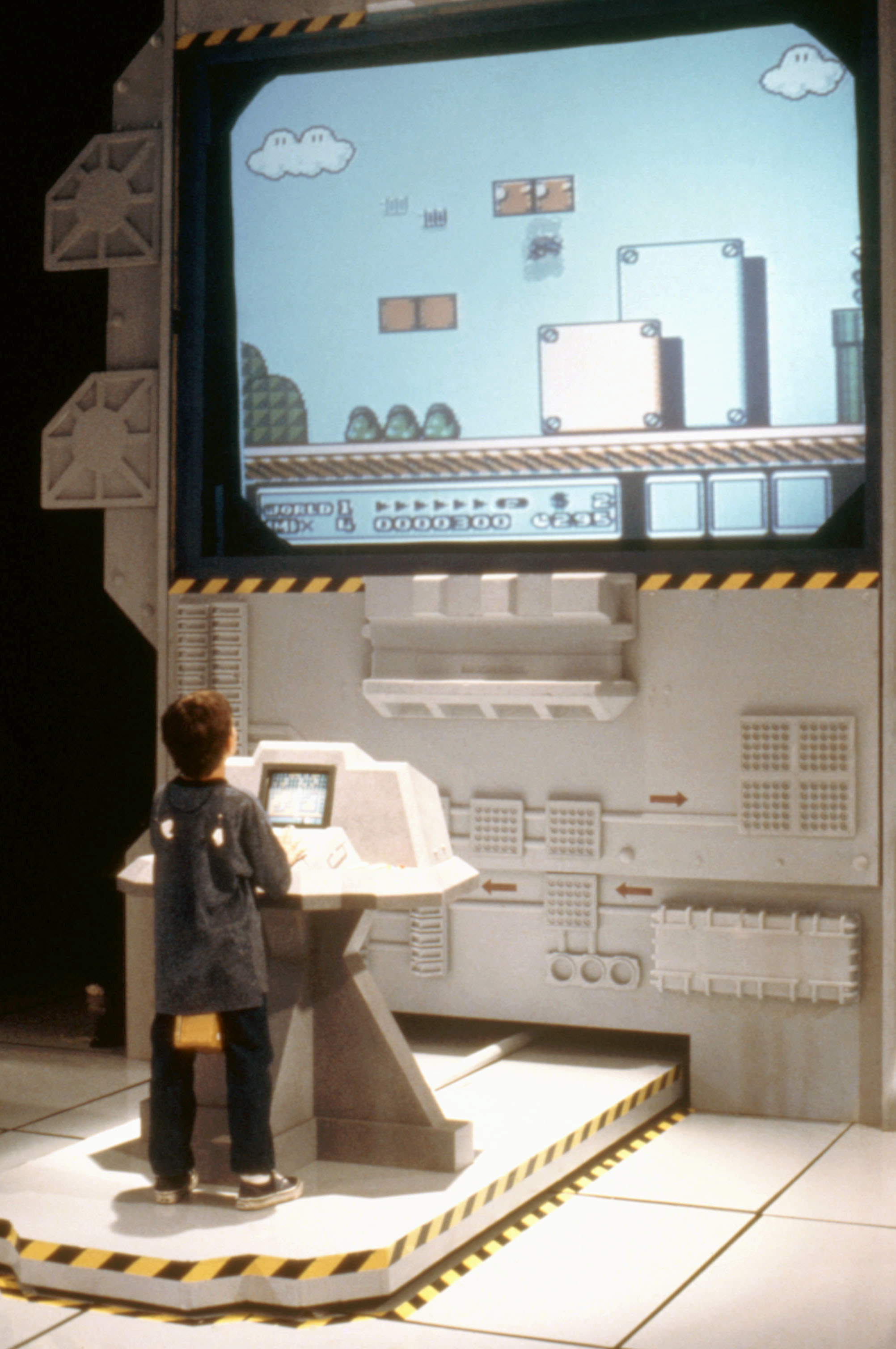 a kid standing to play a video game on a huge screen