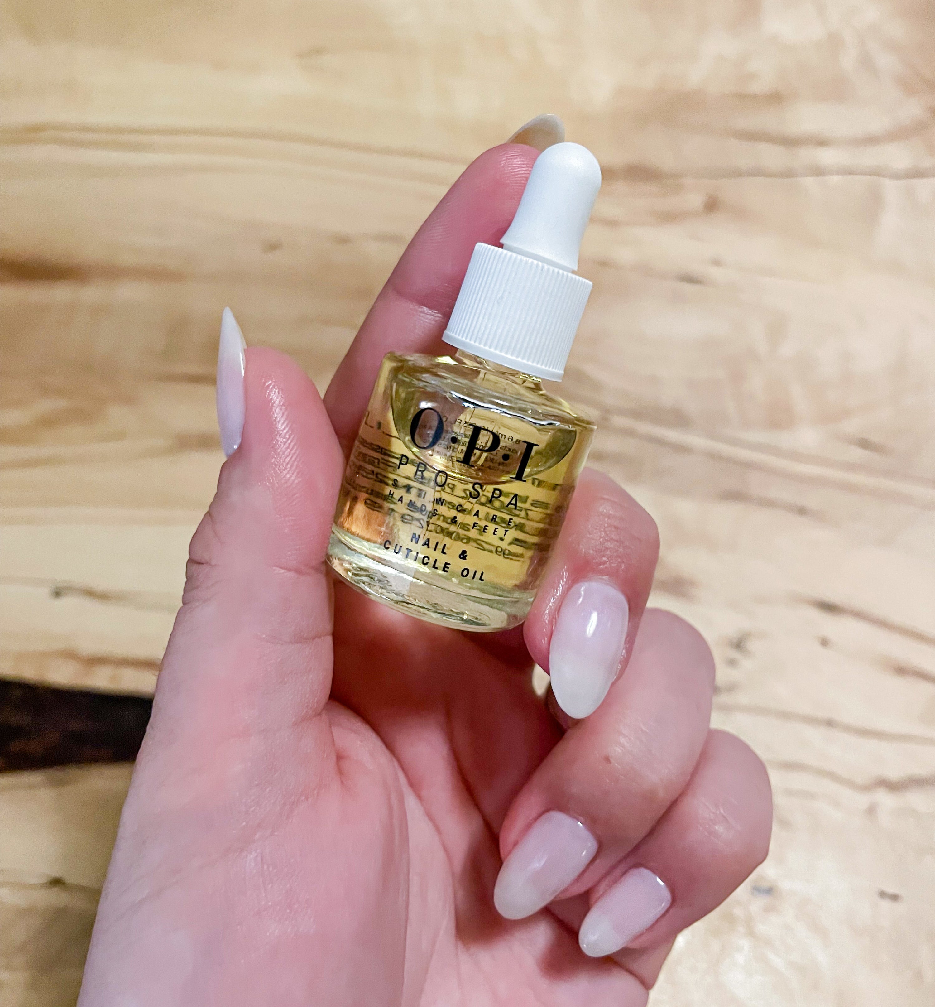 victoria holding a bottle of the cuticle oil in her fingers