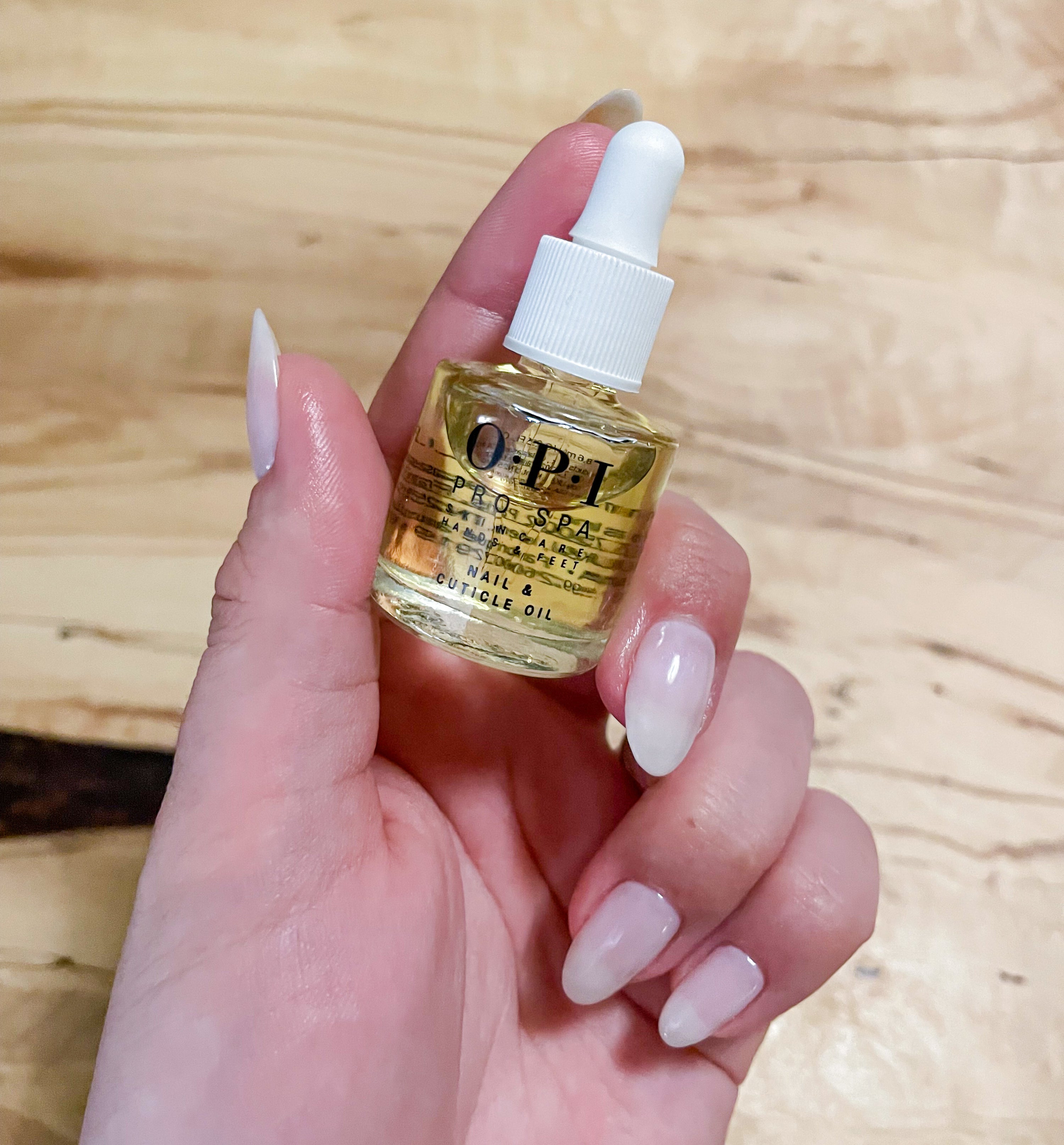 victoria holding a bottle of the cuticle oil in her fingers
