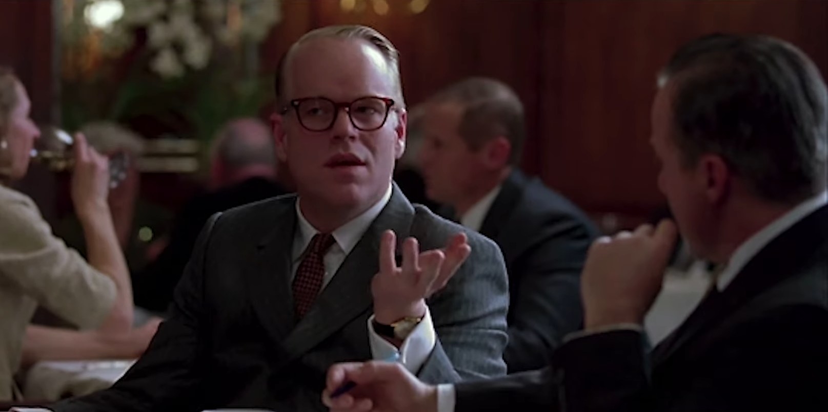 Philip Seymour Hoffman as Truman Captoe, talking to someone at a meal