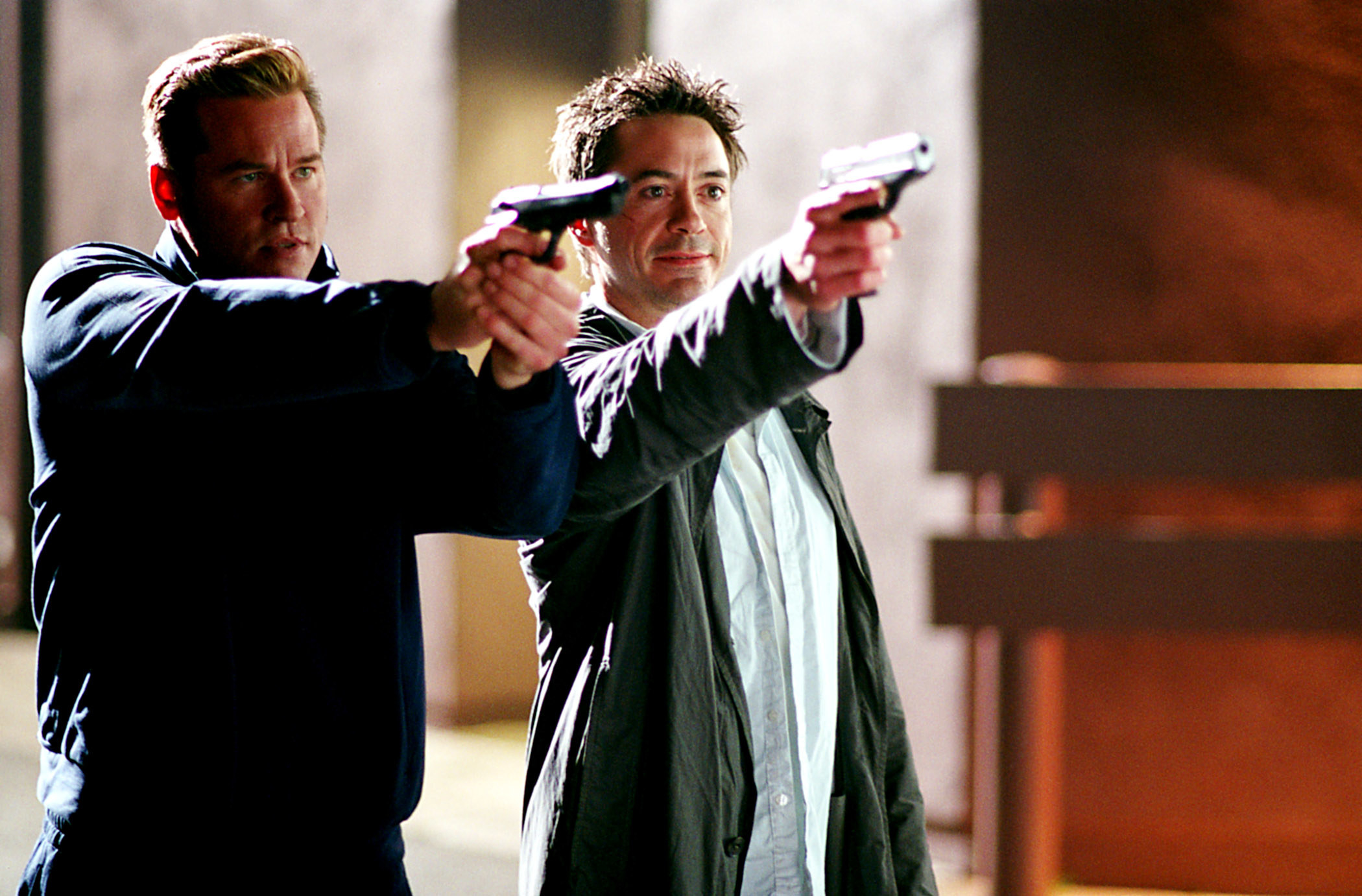 Val Kilmer and Robert Downey Jr pointing guns at something off screen