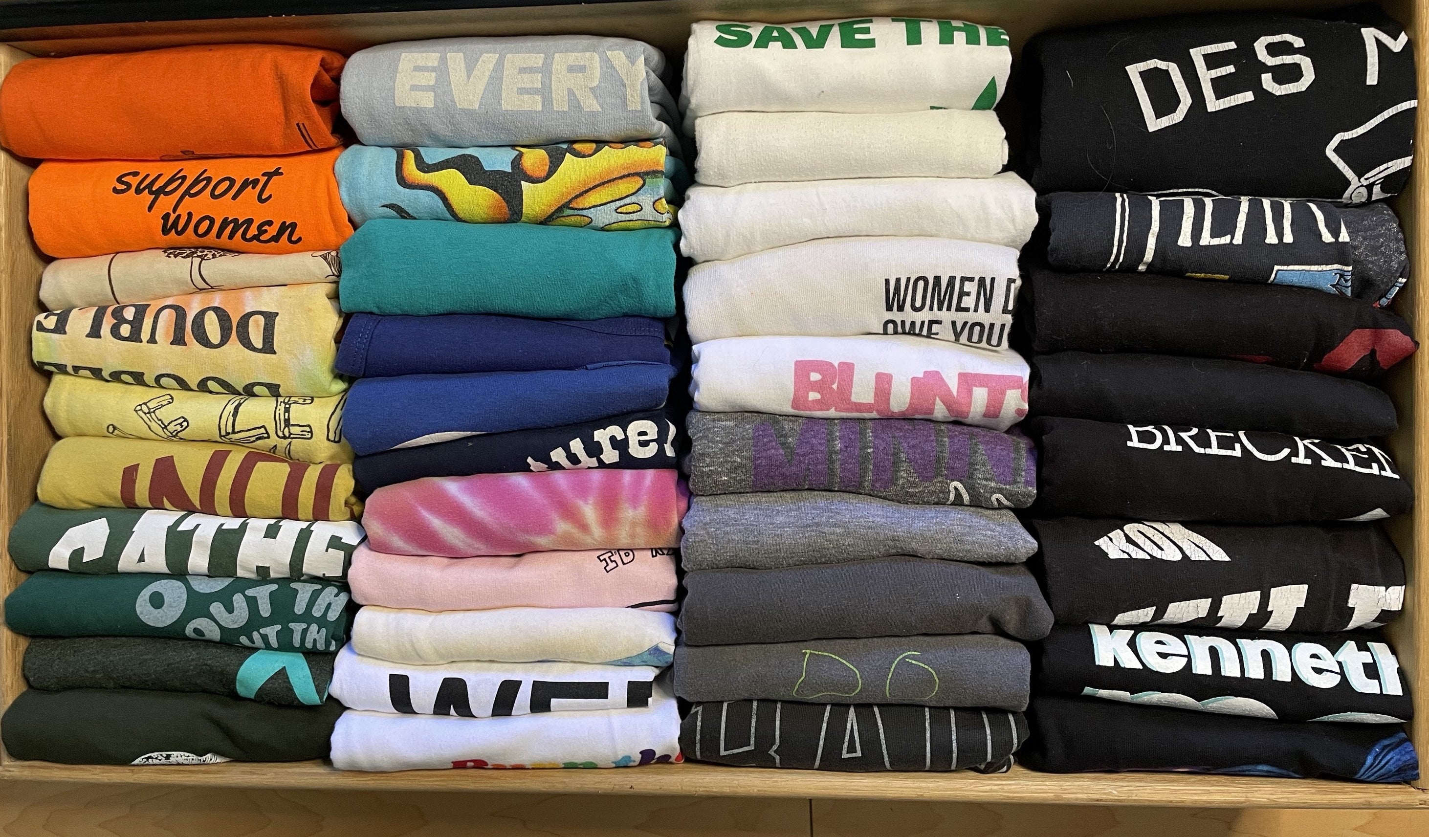 Lots of graphic T-shirts, folded and organized neatly so their graphics are clearly visible from above