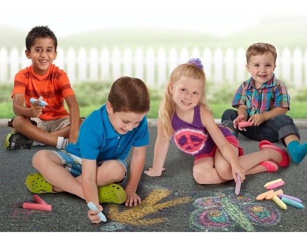 Four kids using chalk on black top