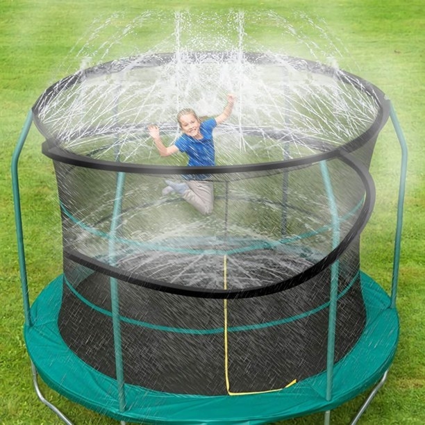 Boy jumping on trampoline with water spraying