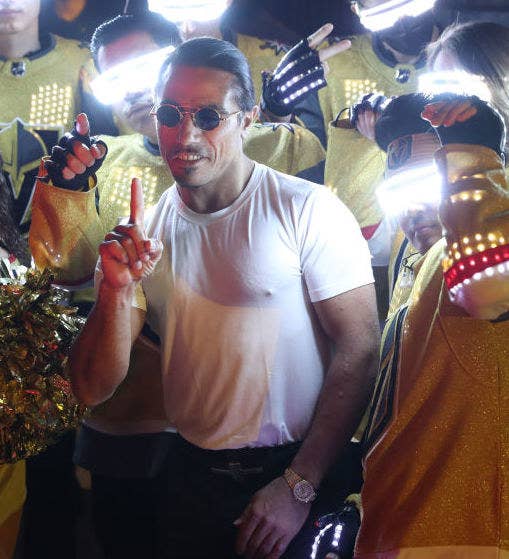Man in a T-shirt and sunglasses and his hand in the air with his pointy finger raised