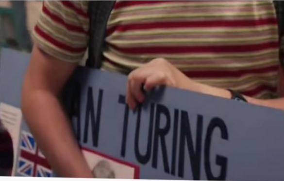A close-up of Will carrying a posterboard of a school project dedicated to Alan Turing