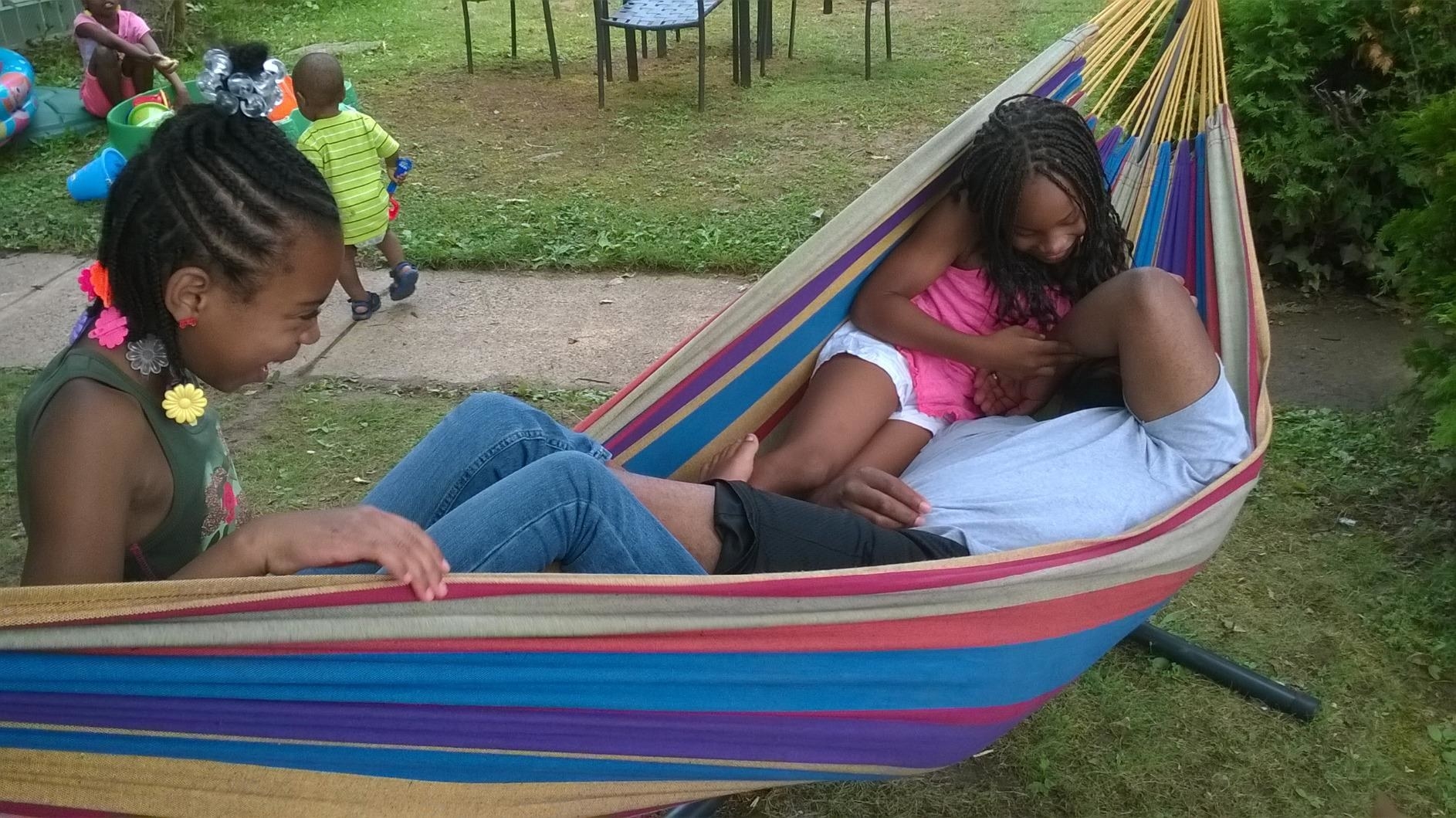 reviewer&#x27;s photo showing adult and two kids hanging in the hammock