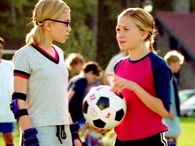 Mary Kate and Ashley chat as they hold a football on a pitch