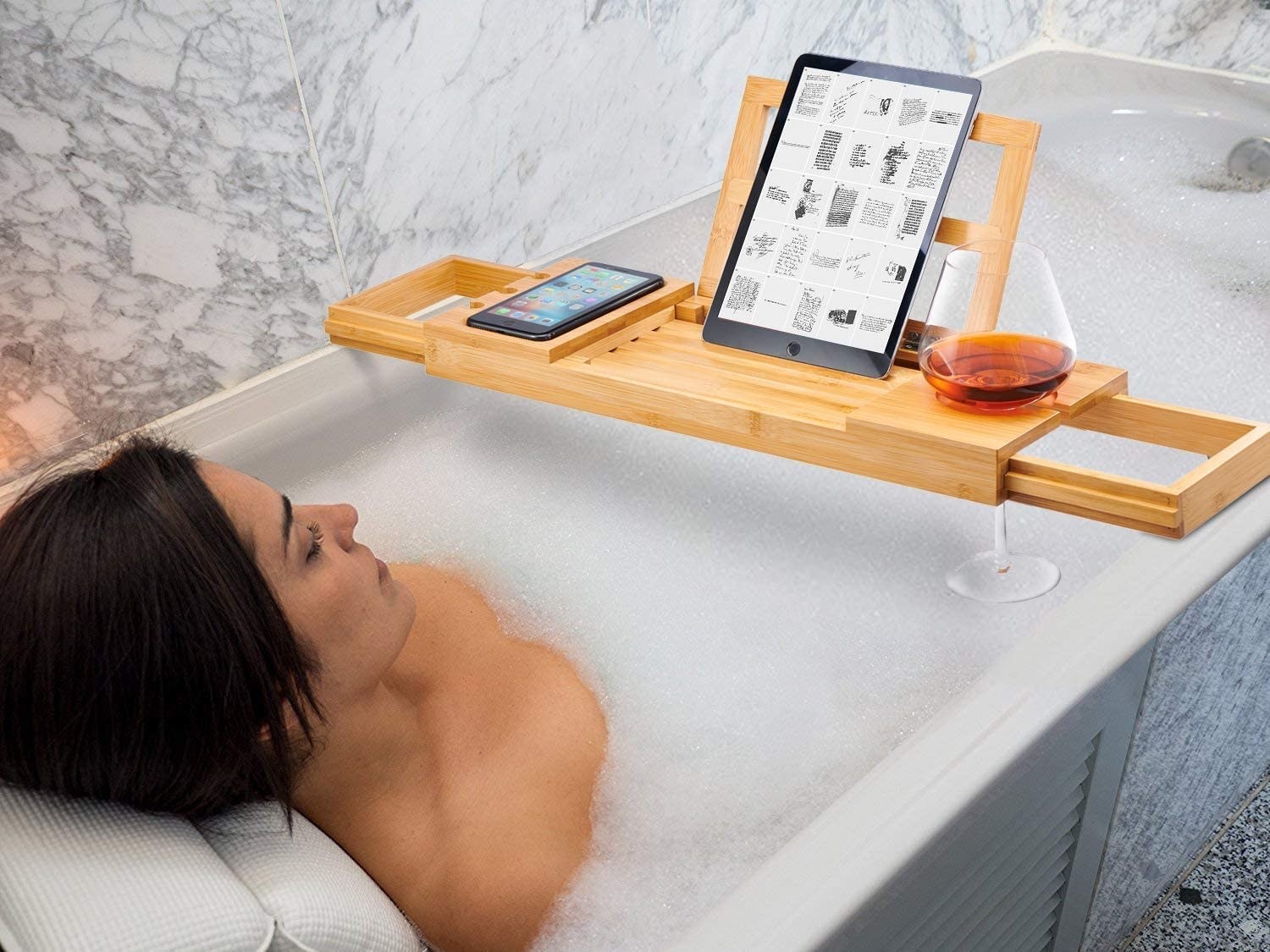 a person relaxing in the tub while watching a show on the tablet perched on their tub caddy