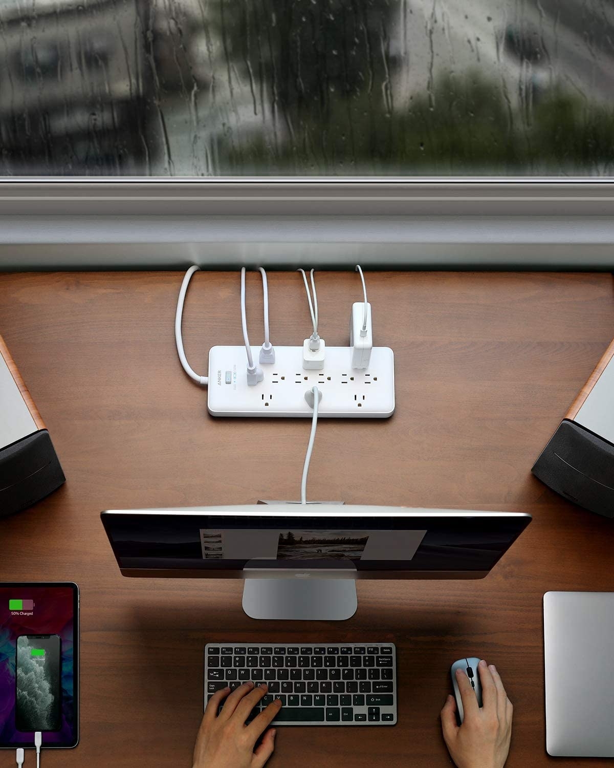 The power strip behind a monitor on a desk
