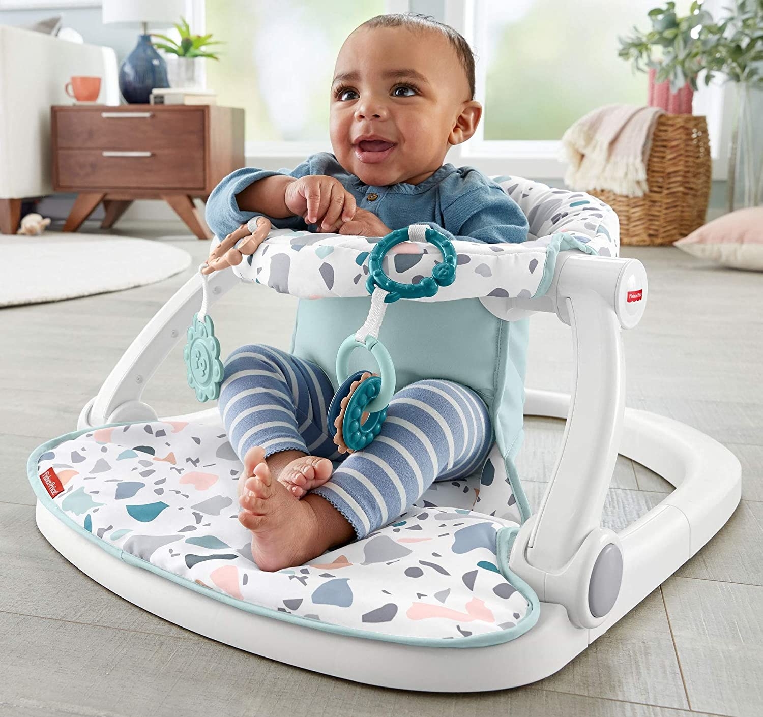 A baby in the baby chair in the middle of a living room