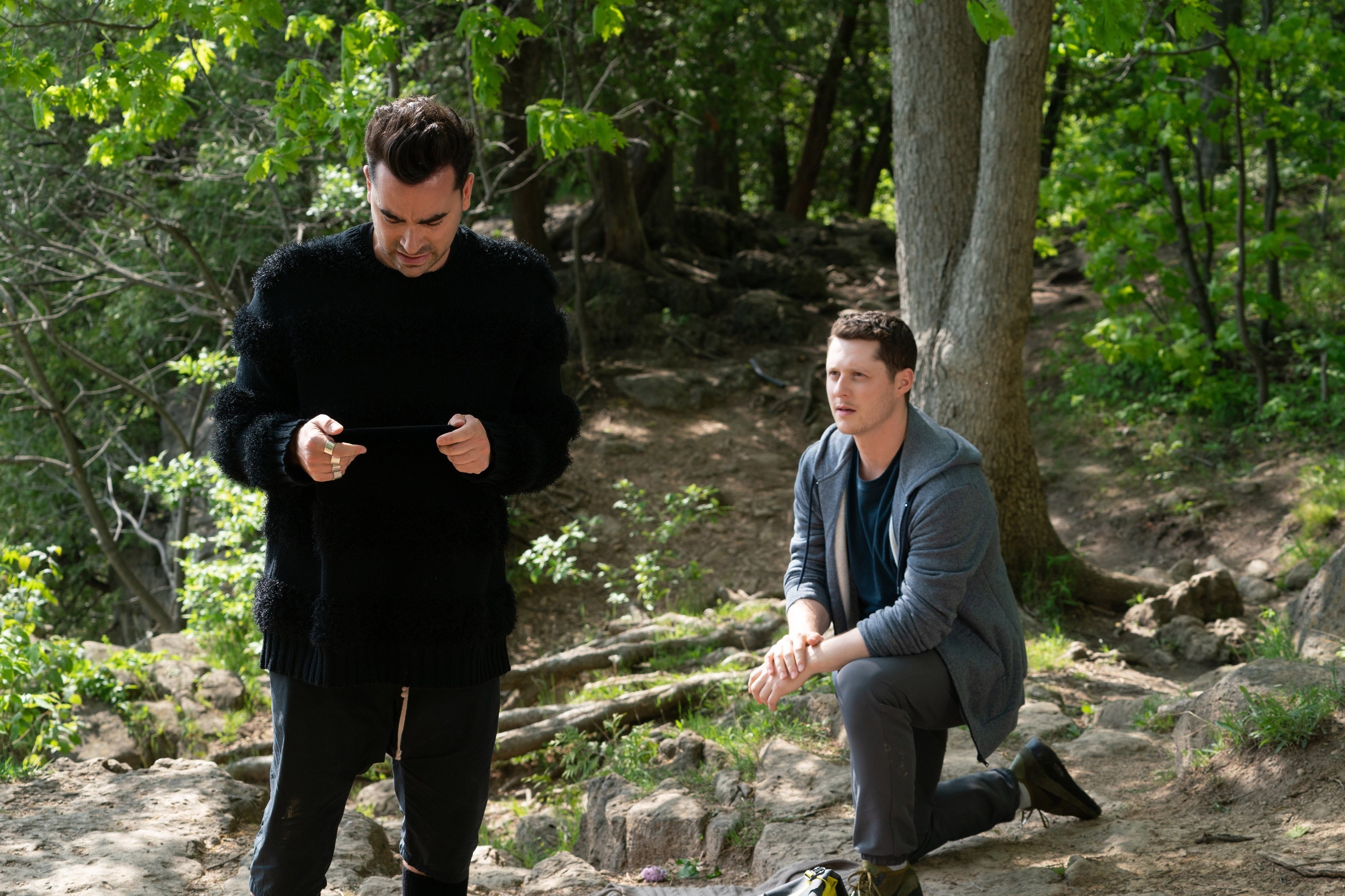 Noah Reid as Patrick Brewer kneels behind Dan Levy as David Rose in &quot;Schitt&#x27;s Creek&quot;