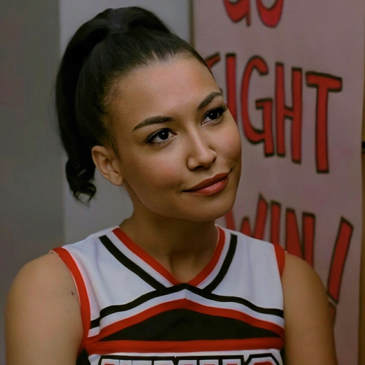 Santana smiling while wearing her cheerleading outfit