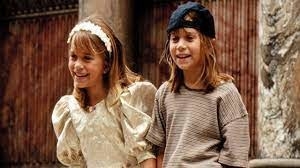 Mary Kate and Ashley laugh standing next to each other