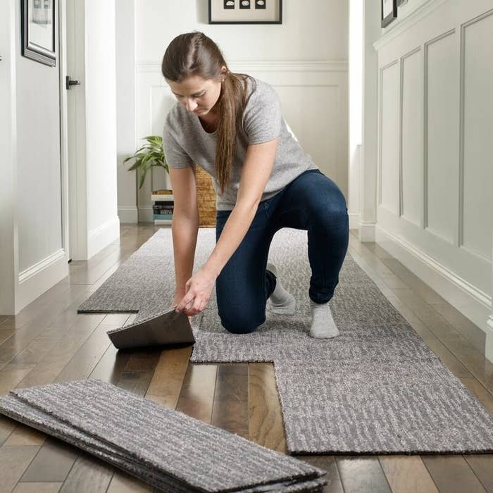 A model putting down grey peel-and-stick carpet