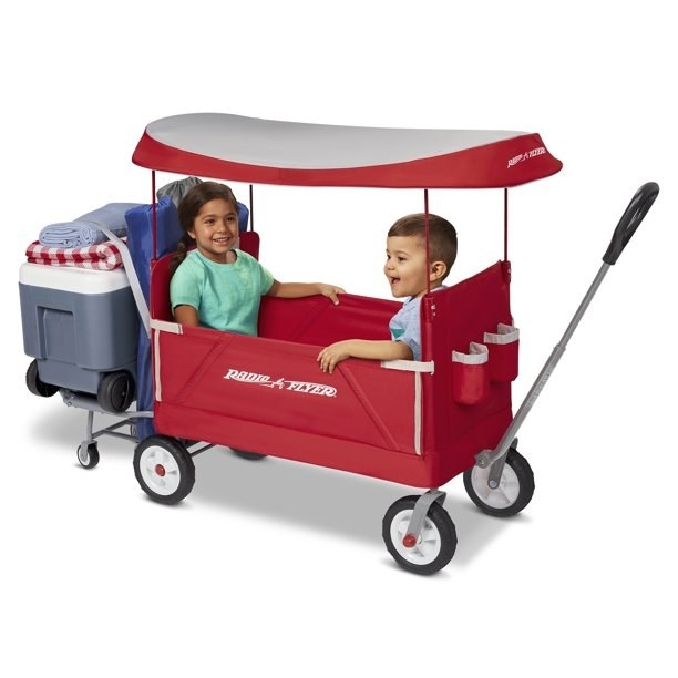 Two kids sitting in red wagon with ice chest on the back