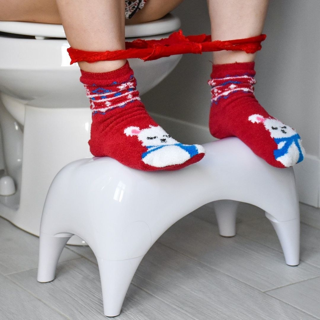 a person&#x27;s feet resting on the stylish toilet stool
