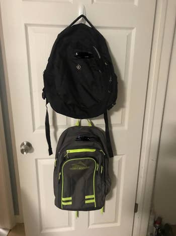 two backpacks hung on a door with command hooks