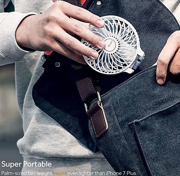 A person putting the fan into their bag
