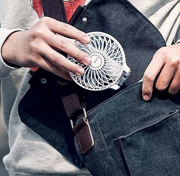 A person putting the fan into their bag
