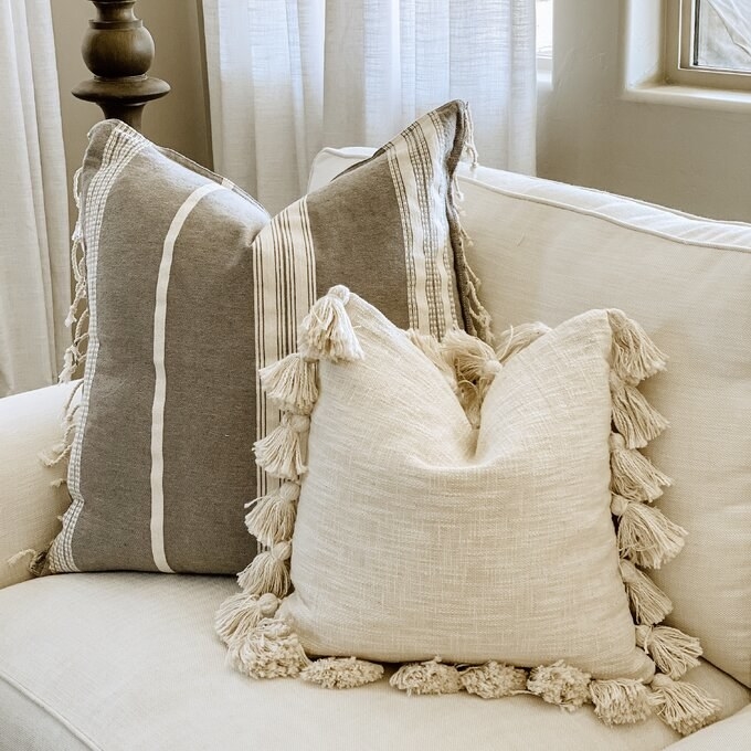 A cream throw pillow with tassels