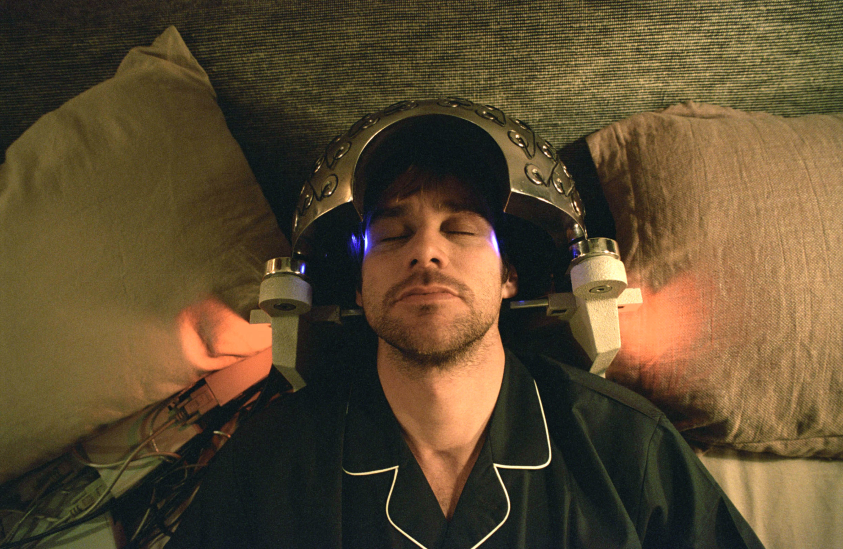 A man sleeps with a strange dome-shaped machine on his head