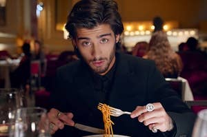 Zayn from One Direction looking up from his plate of spaghetti in a fancy restaurant in the Night Changes music video
