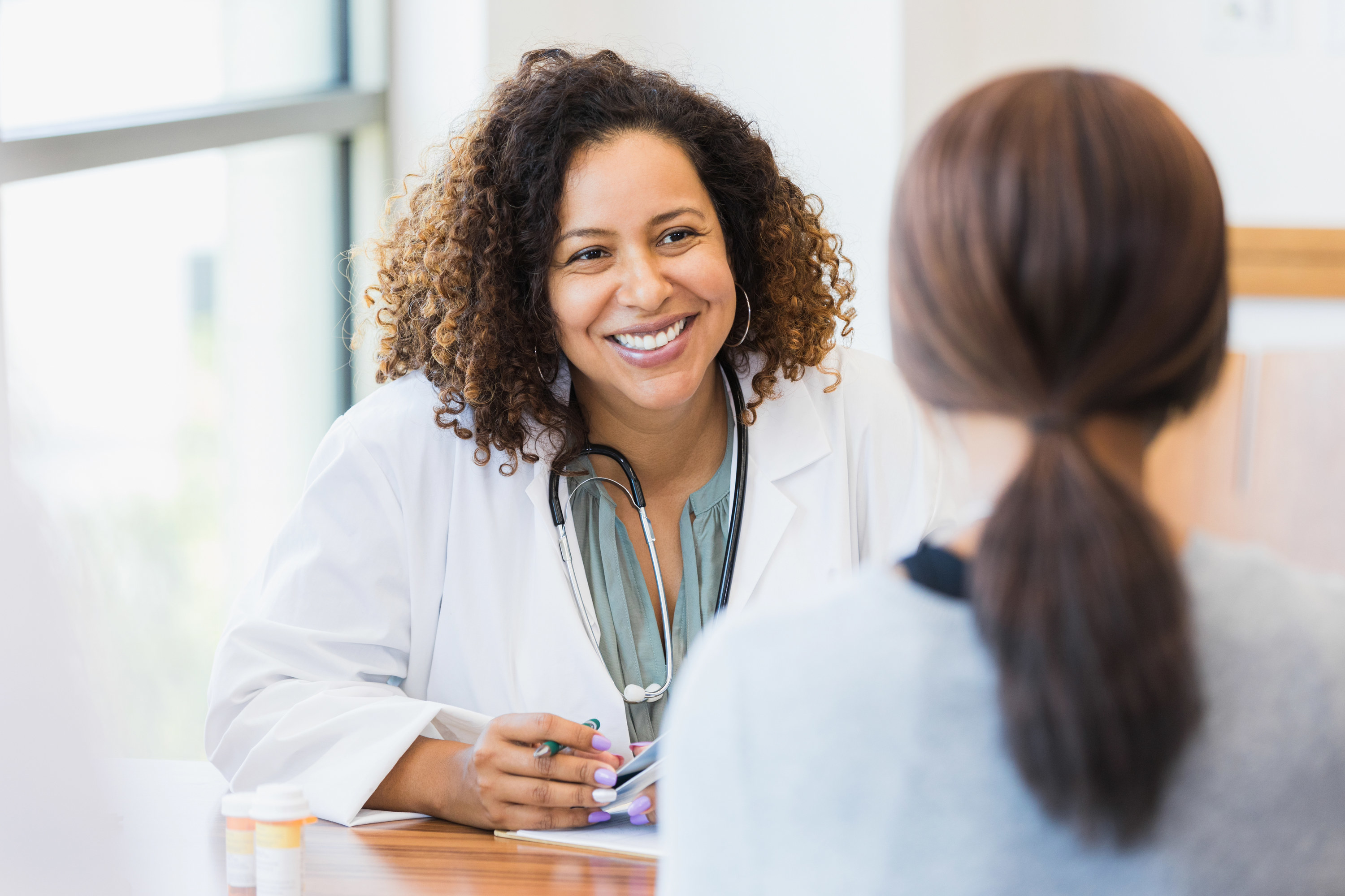 A female doctor smiles as she speaks with a patient