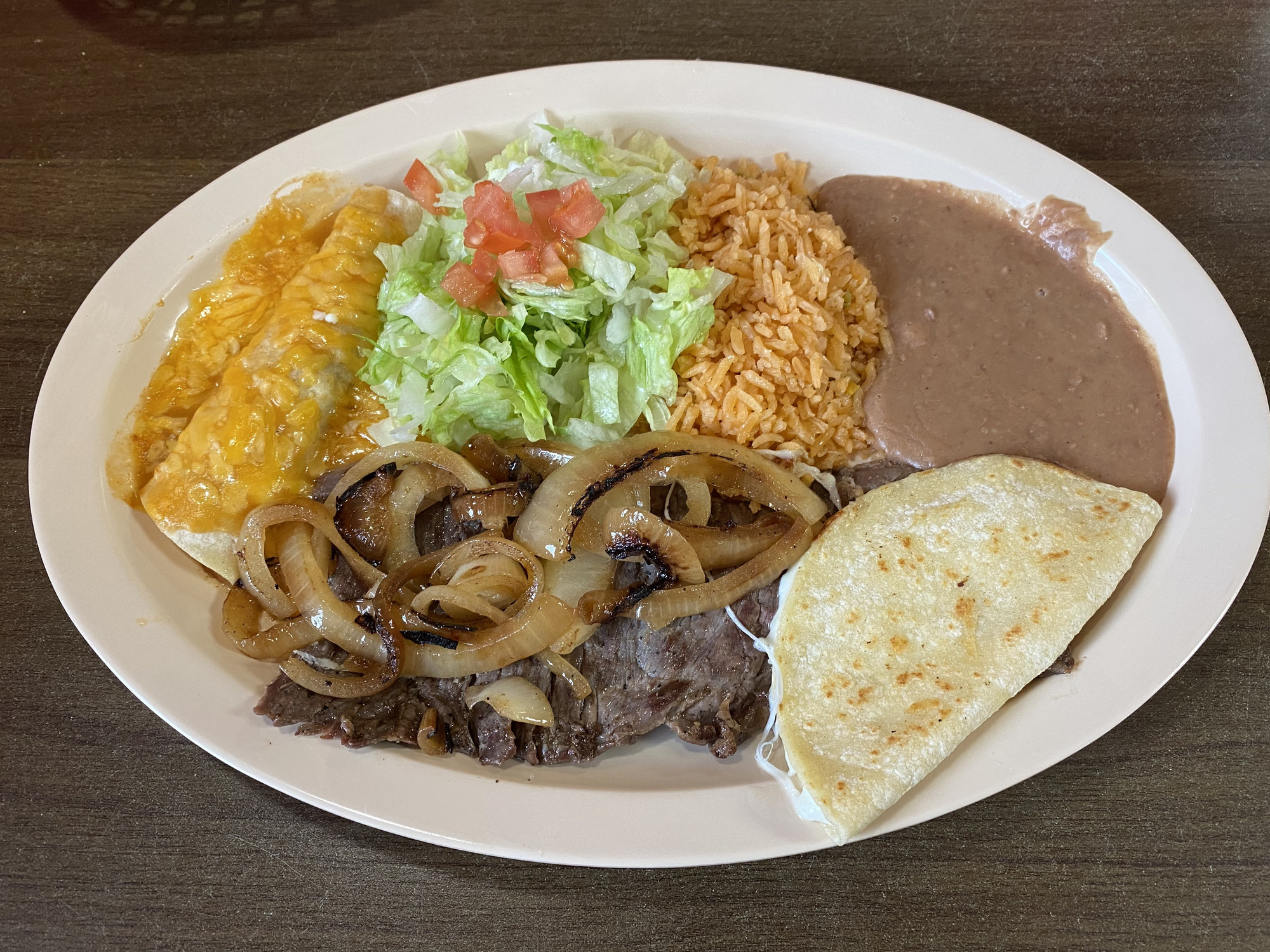 plate of rice, refried beans, an enchilada, steak and onions, and quesadila