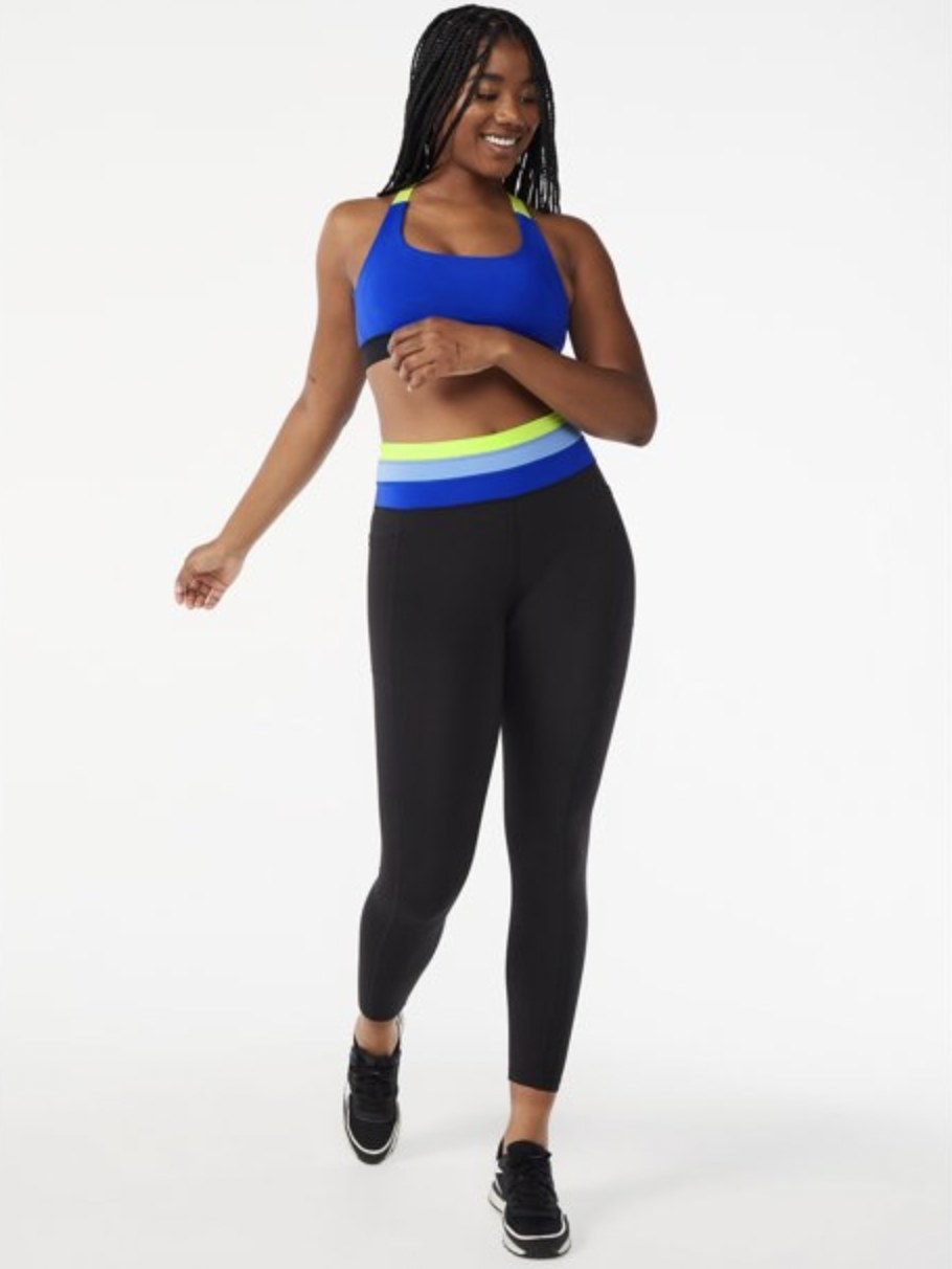 A person wearing a blue sports bra with matching bottoms and black sneakers